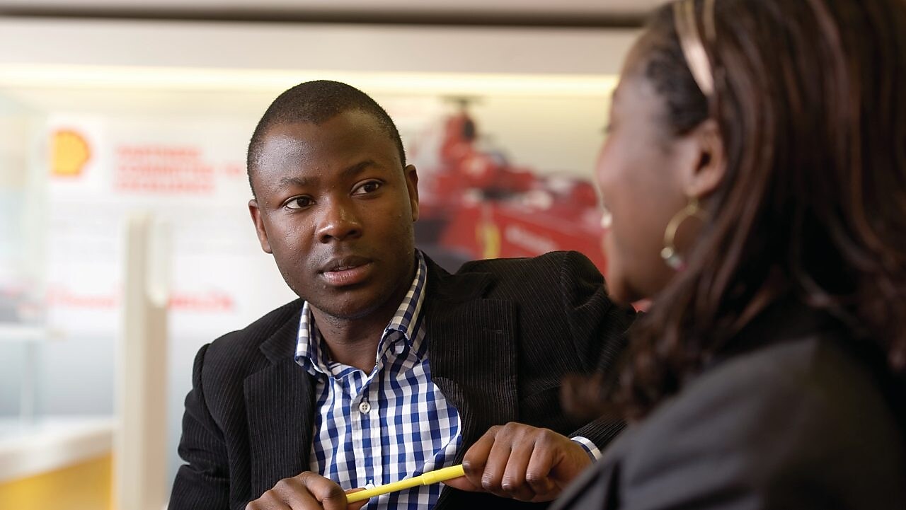 Discussion professionnelle entre deux personnes dans un bureau de Shell.