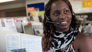 Représentante du service client de Shell portant un casque dans un environnement de bureau, vêtue d'une tenue à motifs noir et blanc.