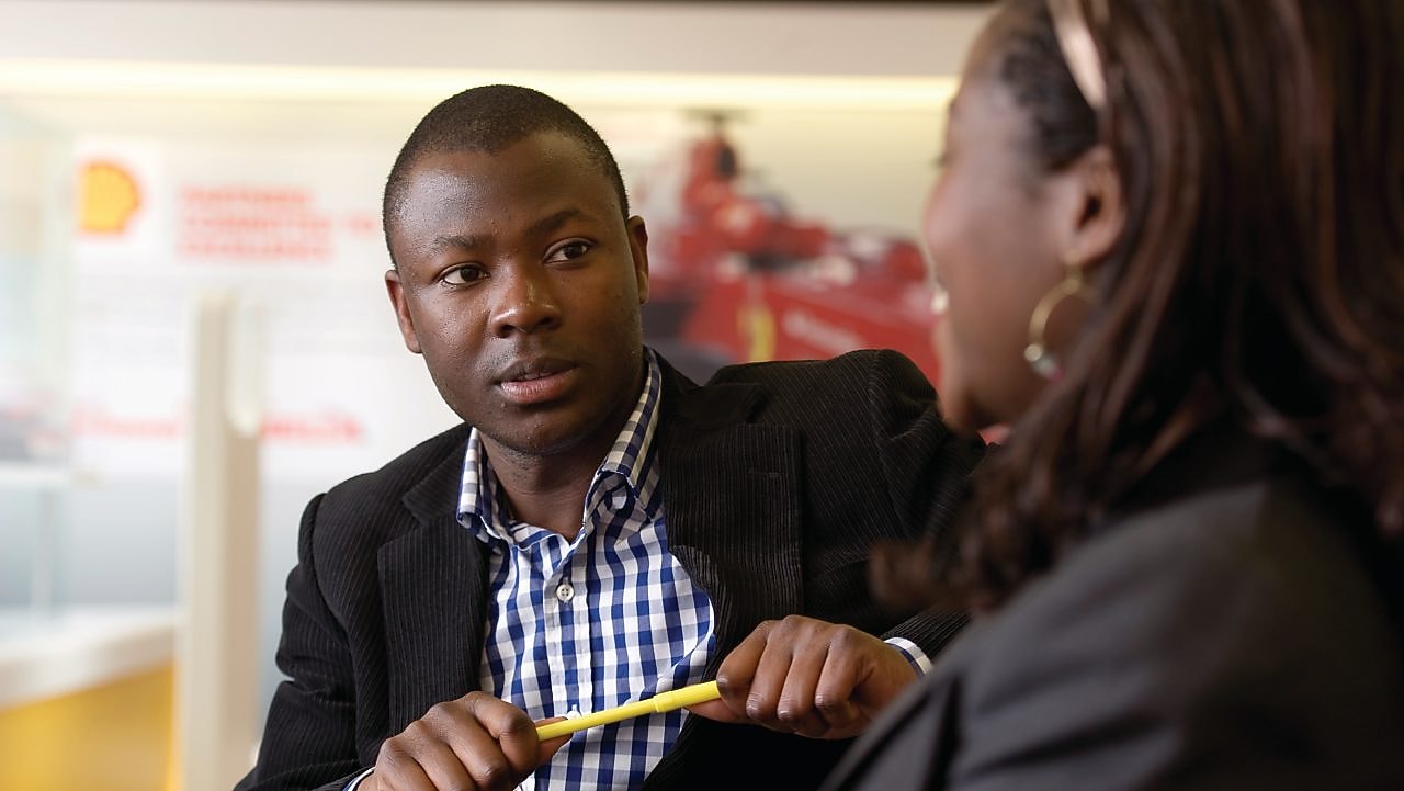 Discussion professionnelle entre deux personnes dans un bureau de Shell.