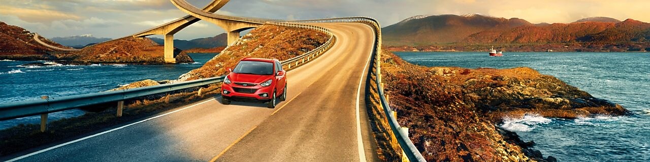 Voiture rouge circulant sur une route au bord d'une rivière