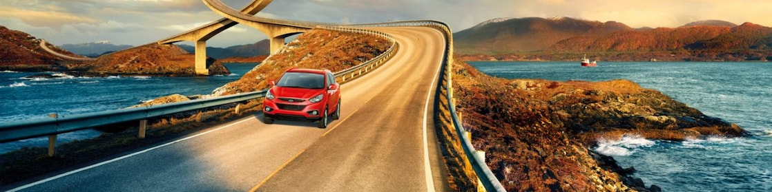 Voiture rouge circulant sur une route au bord d'une rivière
