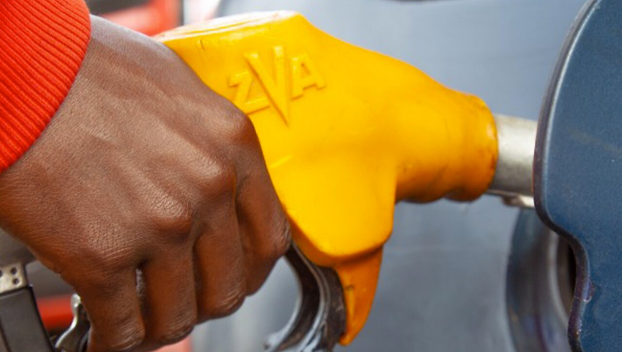 Main tenant un pistolet de pompe à essence jaune lors du ravitaillement d'un véhicule.