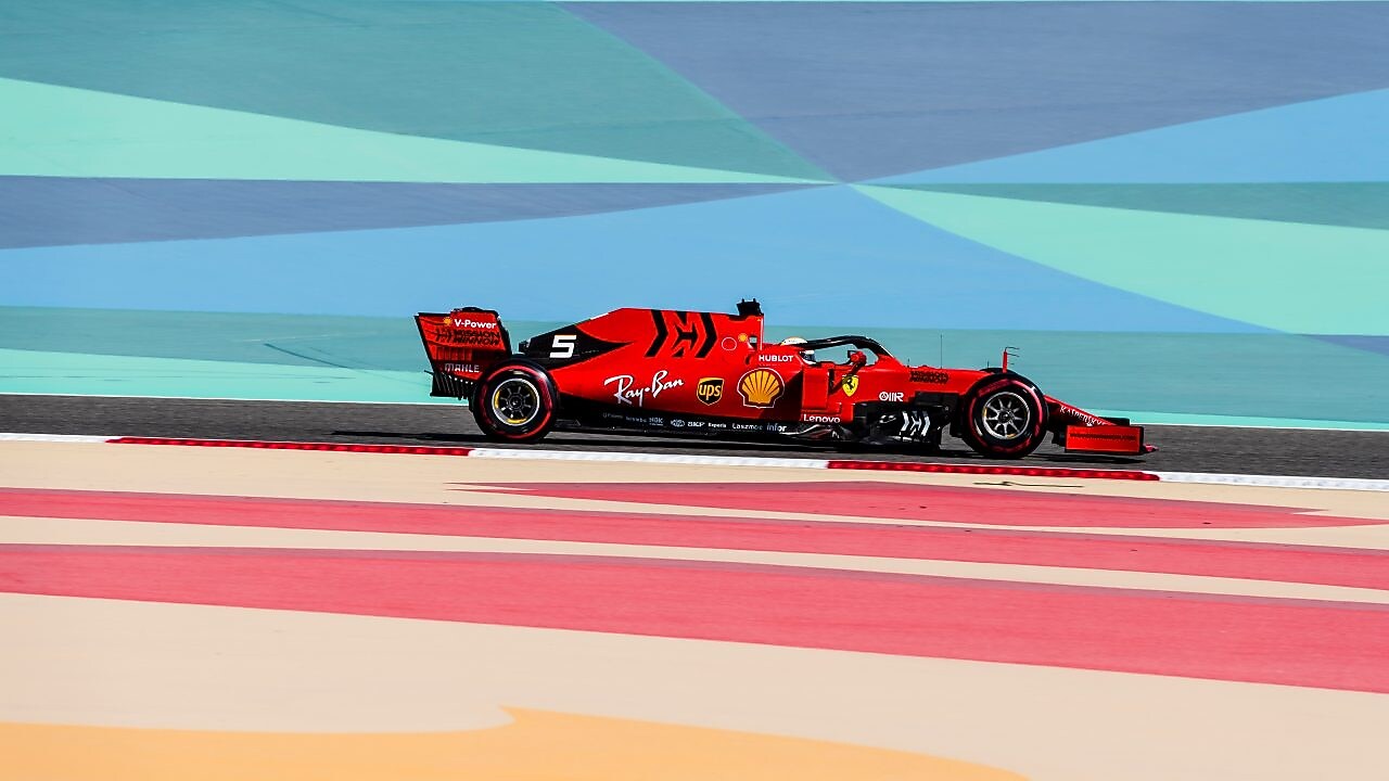 Voiture Ferrari de Formule 1 rouge sur circuit avec bandes colorées, lors d'une course à Bahreïn