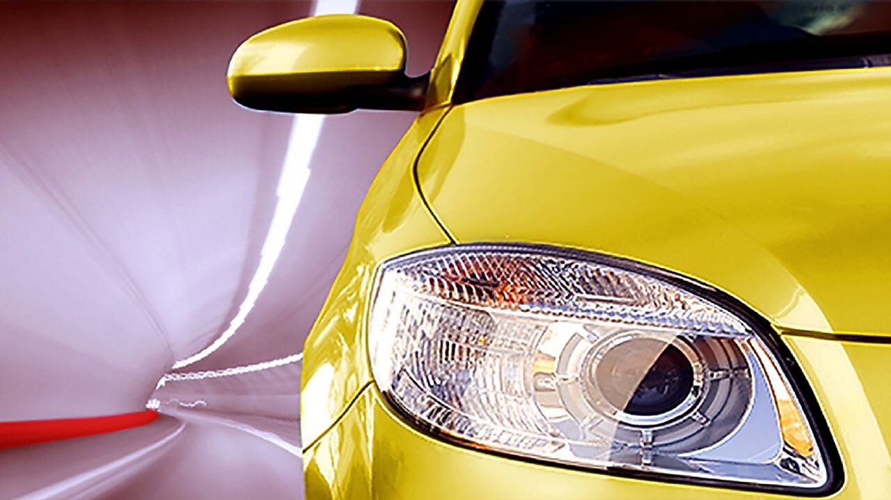 Gros plan sur le phare avant et le rétroviseur d'une voiture jaune moderne avec un arrière-plan flou.