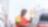 Employé souriant en uniforme Shell fait le plein d'essence à une pompe, avec le logo Shell visible en arrière-plan.