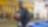 Idrissa Gana Gueye en blouson noir tenant un café devant une boutique Select, appuyé contre une voiture bleue