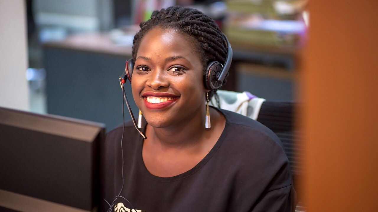 Représentante du service client portant un casque-micro dans un centre d'appels, souriant avec professionnalisme.
