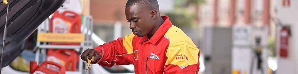 Champion de service Shell en train de vérifier le niveau d'huile d'une voiture