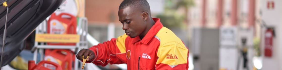 Champion de service Shell en train de vérifier le niveau d'huile d'une voiture