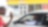 Deux personnes se saluant devant une boutique  Shell Select, l'une dans une voiture et l'autre debout à l'extérieur.