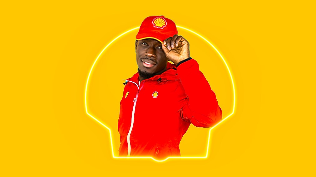 Un employé Shell saluant joyeusement avec un sourire, portant une casquette et une veste rouges sur fond jaune lumineux.