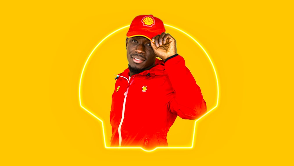 Un employé Shell saluant joyeusement avec un sourire, portant une casquette et une veste rouges sur fond jaune lumineux.