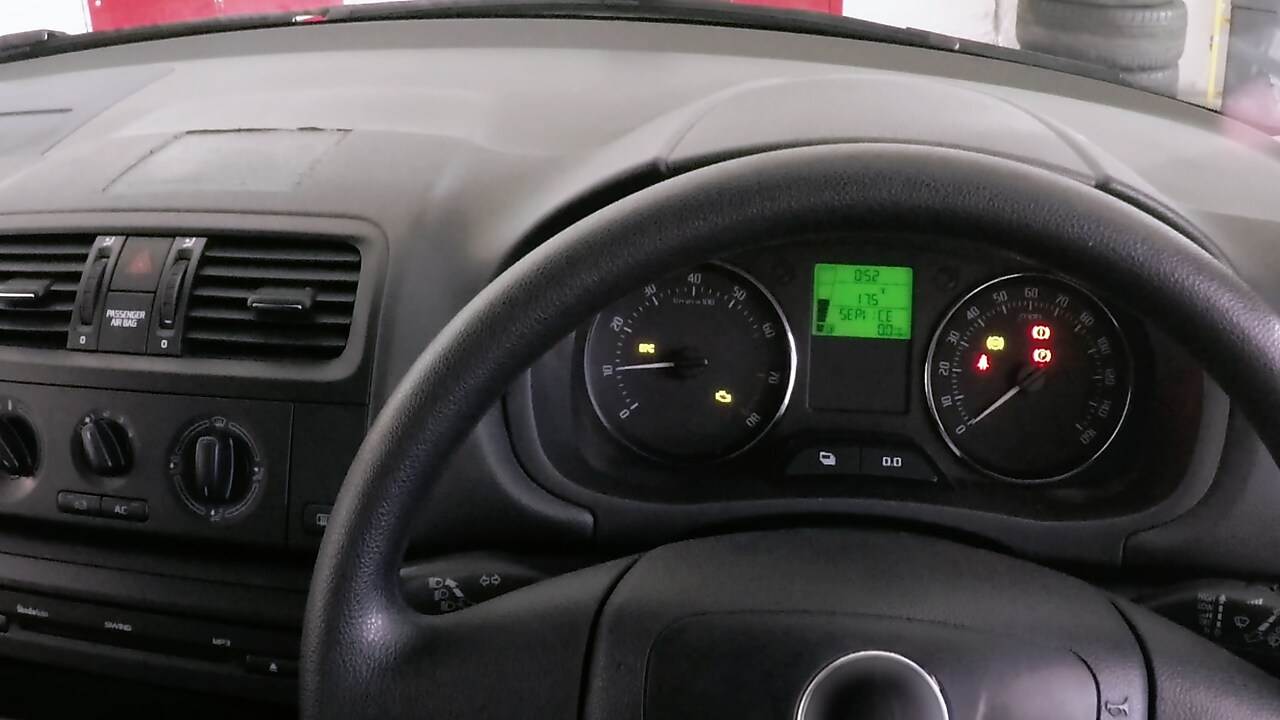 Tableau de bord d'une voiture montrant les cadrans et voyants allumés, avec un écran LCD vert affichant des informations