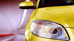 Gros plan sur le phare avant et le rétroviseur d'une voiture jaune moderne avec un arrière-plan flou.