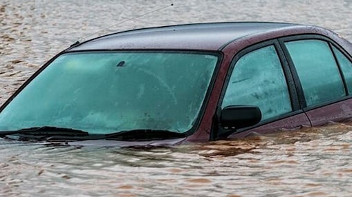 Voiture berline bordeaux partiellement submergée dans des eaux de crue