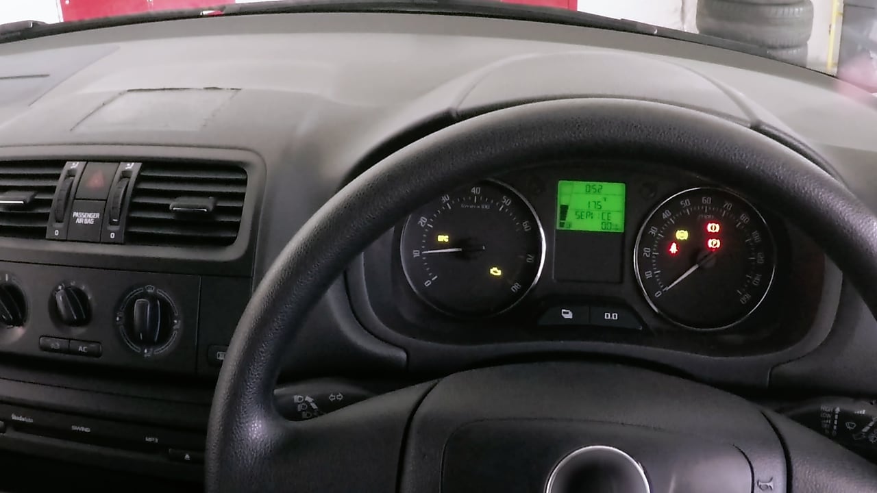 Tableau de bord d'une voiture montrant les cadrans et voyants allumés, avec un écran LCD vert affichant des informations