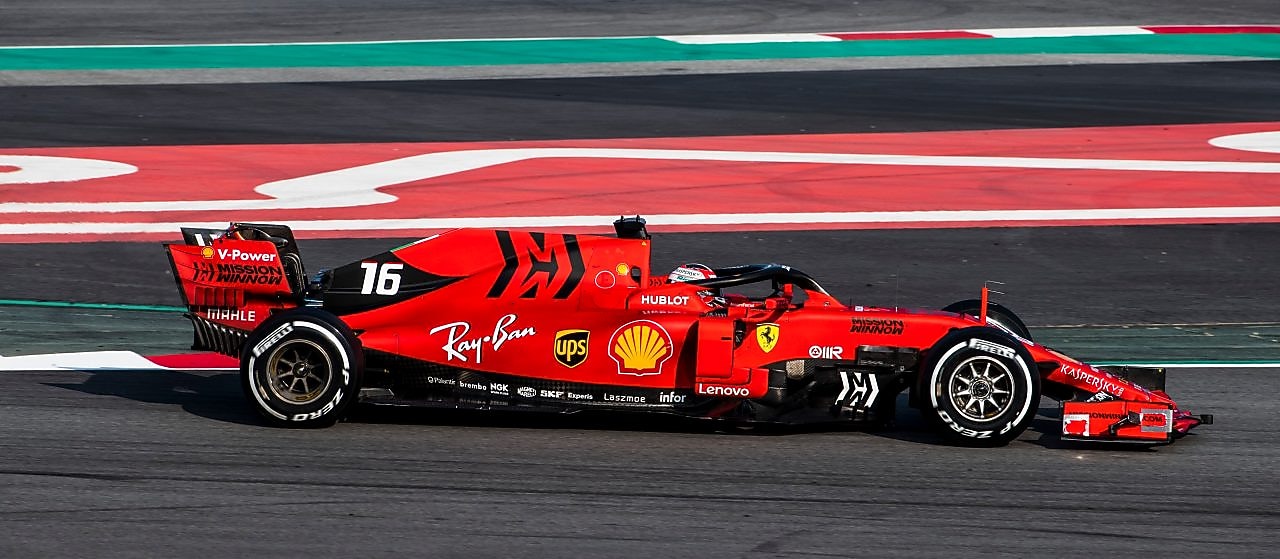 Voiture Ferrari F1 numéro 16 en action sur un circuit de course avec bordures rouge et vert