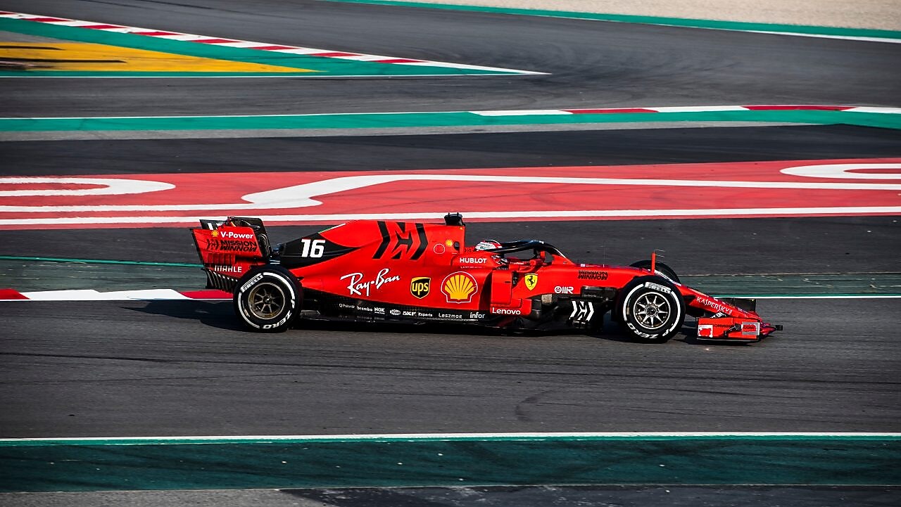 Voiture Ferrari F1 numéro 16 en action sur un circuit de course avec bordures rouge et vert
