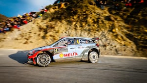 Voiture de rallye Hyundai i20 WRC en action lors du Rallye Monte-Carlo, avec des spectateurs sur la falaise en arrière-plan
