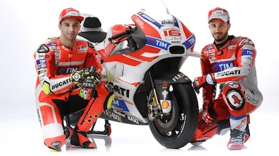 Deux pilotes de course en combinaison rouge Ducati posant avec leur moto de MotoGP aux couleurs de l'équipe TIM