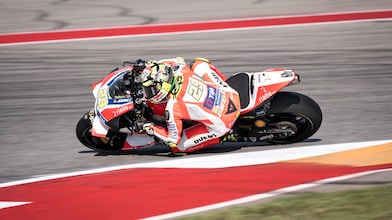 Moto Ducati rouge et blanche n°29 en plein virage sur un circuit de course aux bordures rouges et blanches.