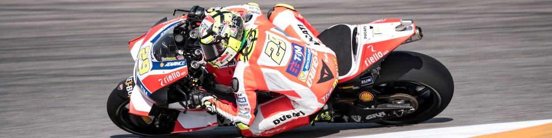 Moto Ducati rouge et blanche n°29 en plein virage sur un circuit de course aux bordures rouges et blanches.