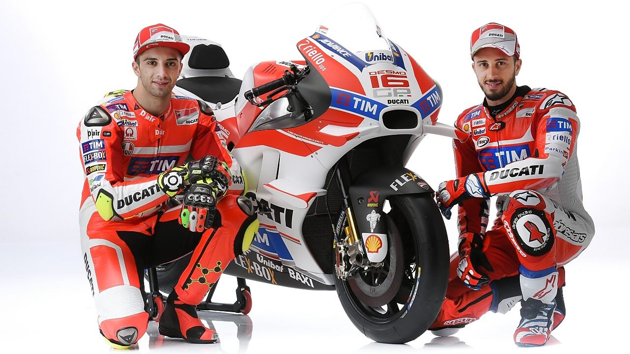 Deux pilotes de course en combinaison rouge Ducati posant avec leur moto de MotoGP aux couleurs de l'équipe TIM