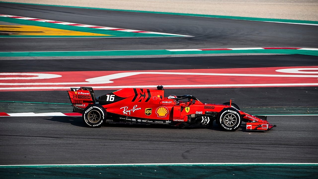 Voiture Ferrari F1 numéro 16 en action sur un circuit de course avec bordures rouge et vert