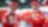 Deux pilotes Ferrari en combinaison rouge et casquette discutent dans le garage de l'équipe pendant un Grand Prix de F1