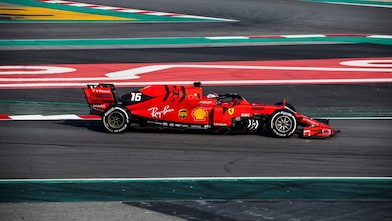 Voiture Ferrari F1 numéro 16 en action sur un circuit de course avec bordures rouge et vert