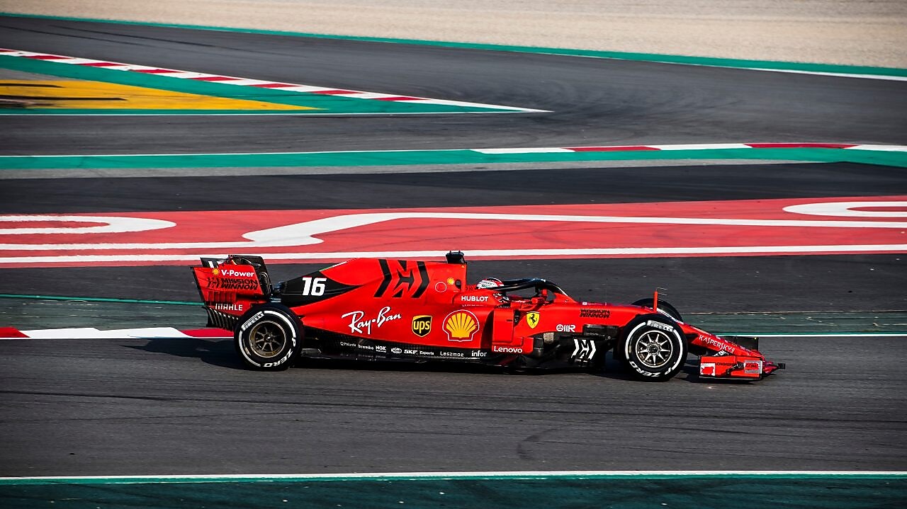 Voiture Ferrari F1 numéro 16 en action sur un circuit de course avec bordures rouge et vert