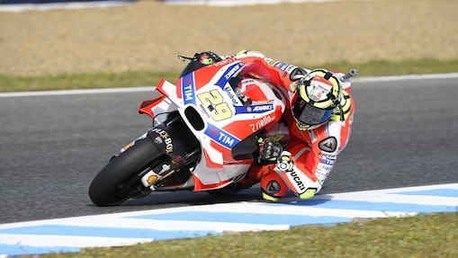 Pilote Ducati MotoGP en plein virage sur sa moto rouge et blanche numéro 29, penché dans un angle extrême sur la piste.