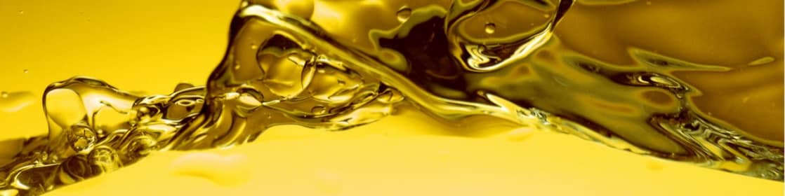 Ondulations et éclaboussures d'huile dorée en gros plan, créant des formes abstraites et liquides sur fond jaune