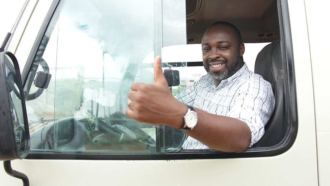Chauffeur souriant faisant un pouce levé depuis la cabine de son camion blanc