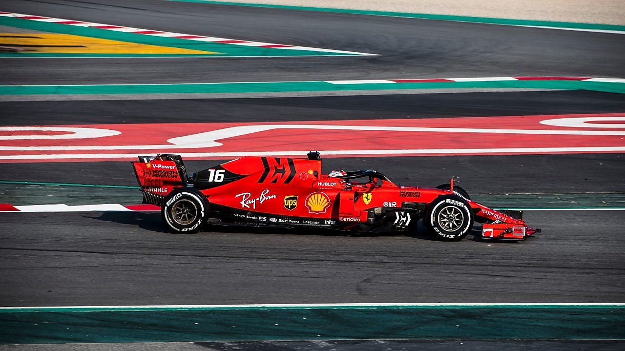 Voiture Ferrari F1 numéro 16 en action sur un circuit de course avec bordures rouge et vert