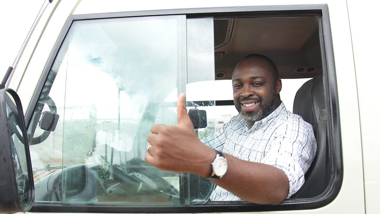 Chauffeur souriant faisant un pouce levé depuis la cabine de son camion blanc