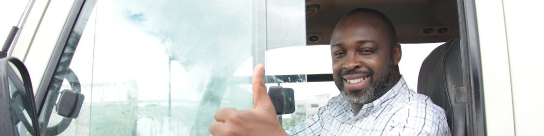 Chauffeur souriant faisant un pouce levé depuis la cabine de son camion blanc