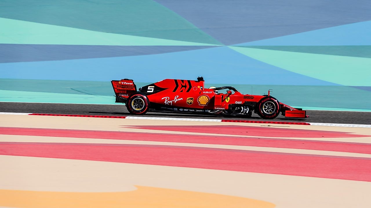 Voiture Ferrari de Formule 1 rouge sur circuit avec bandes colorées, lors d'une course à Bahreïn