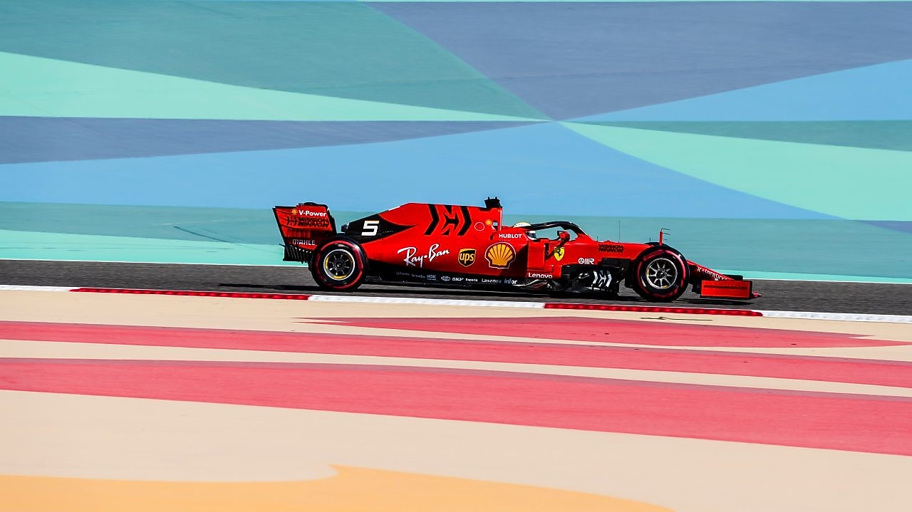 Voiture Ferrari de Formule 1 rouge sur circuit avec bandes colorées, lors d'une course à Bahreïn