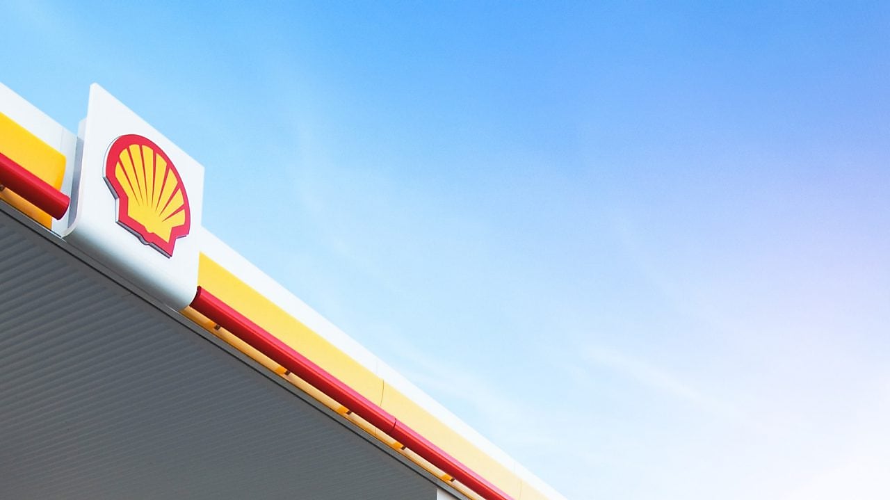 Logo Shell rouge et jaune sur le toit d'une station-service contre un ciel bleu clair