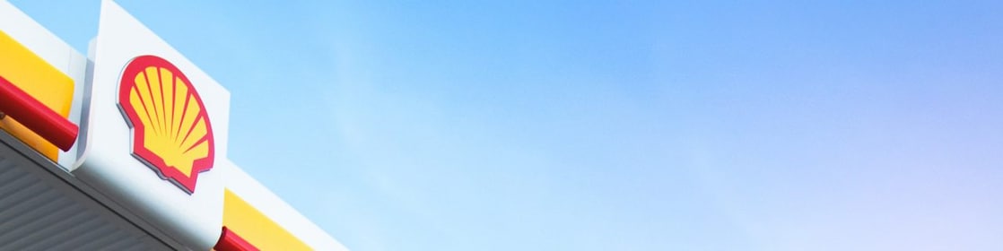 Logo Shell rouge et jaune sur le toit d'une station-service contre un ciel bleu clair