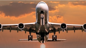 Avion commercial gros-porteur photographié de face au coucher du soleil, avec un ciel orange dramatique en arrière-plan.