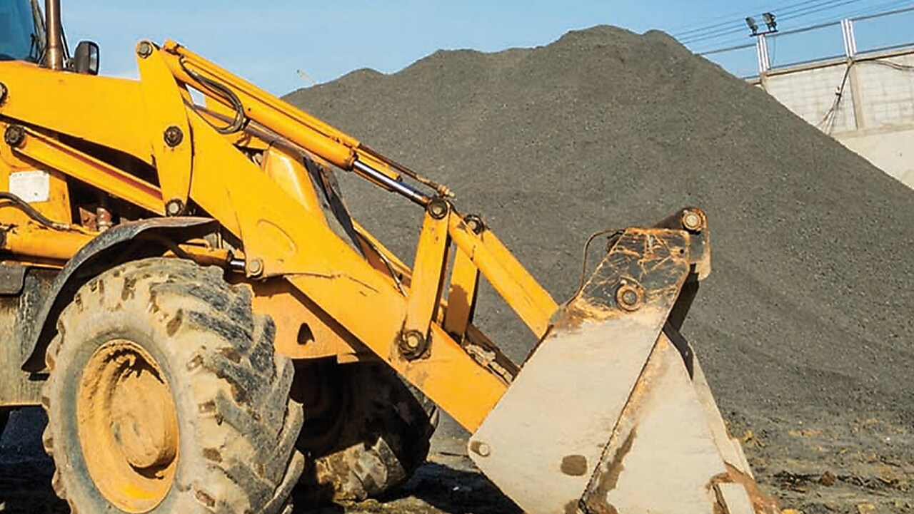 Gros plan sur les roues et la cabine d'un tractopelle jaune couvert de boue sur un chantier de construction.